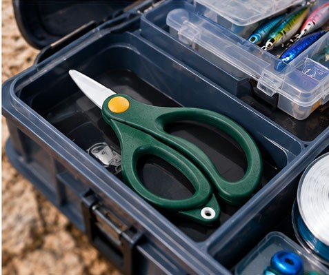 Ceramic fishing scissors stored in an organized tackle box with fishing lures and line.