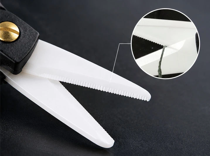 Close-up of white ceramic fishing scissors blades showing the serrated cutting edge