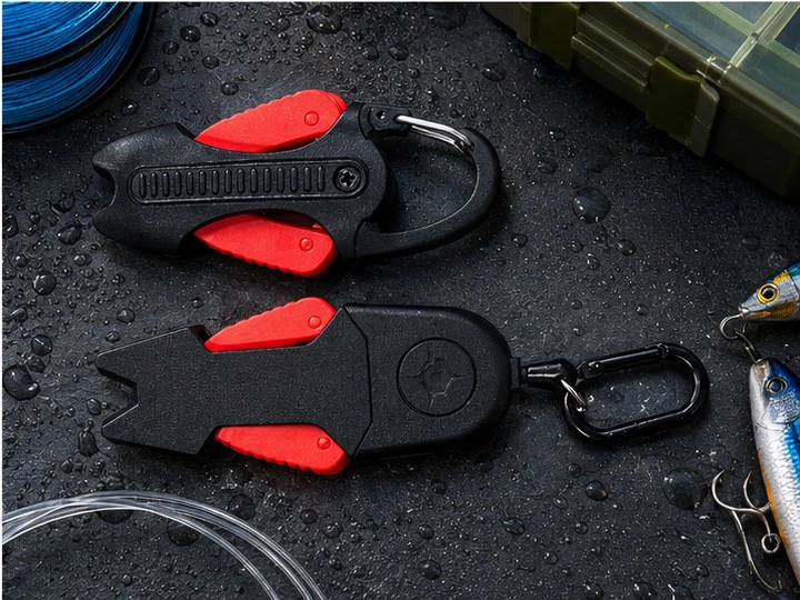 Two black and red fishing line cutters displayed with fishing tackle and fishing line on a wet surface
