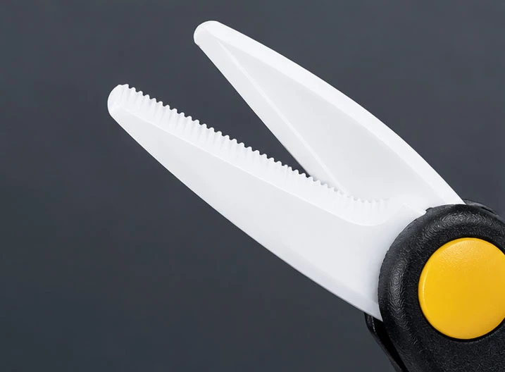 Close-up of ceramic fishing scissors showing the serrated edge on one blade