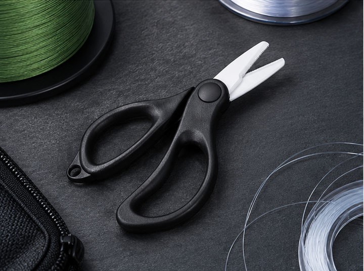 Black-handled ceramic fishing scissors displayed with braided PE line and fishing line spools